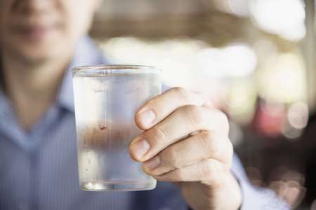 Uomo con in mano un bicchiere di acqua freddissima